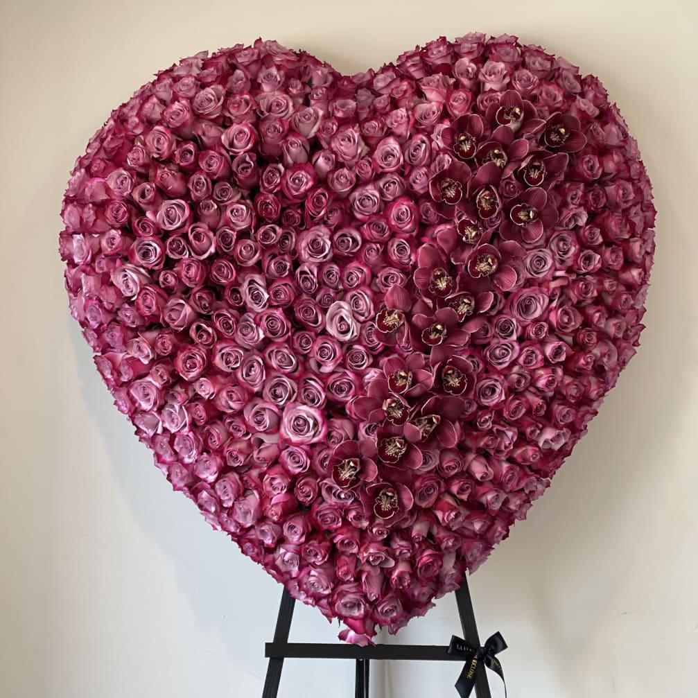 Heart-shaped floral arrangement of pink roses with dark orchids