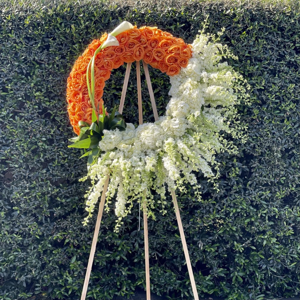 Orange and white floral wreath on a wooden easel