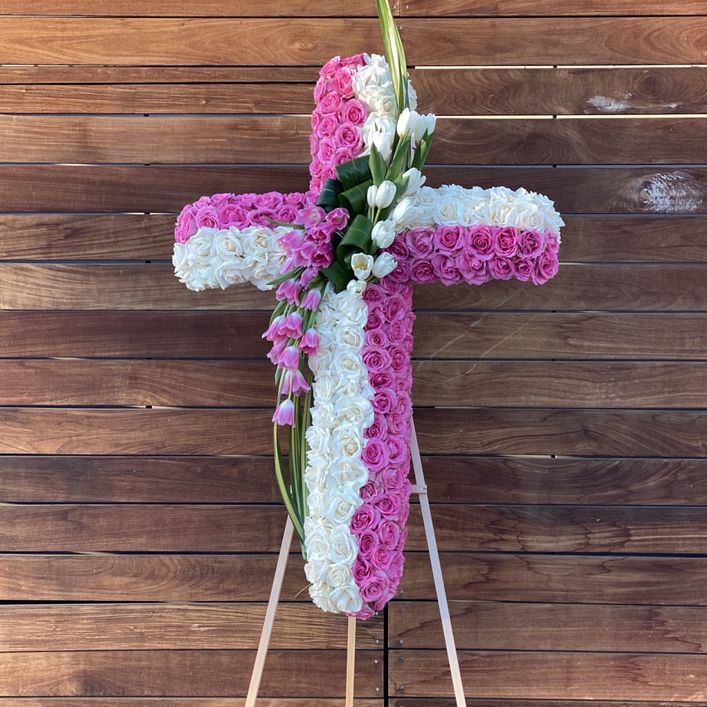 Cross-shaped floral arrangement of pink and white roses on an easel
