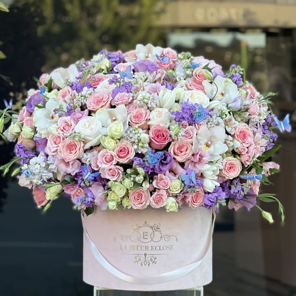 Large pastel bouquet of pink, white, and purple flowers in a pink box