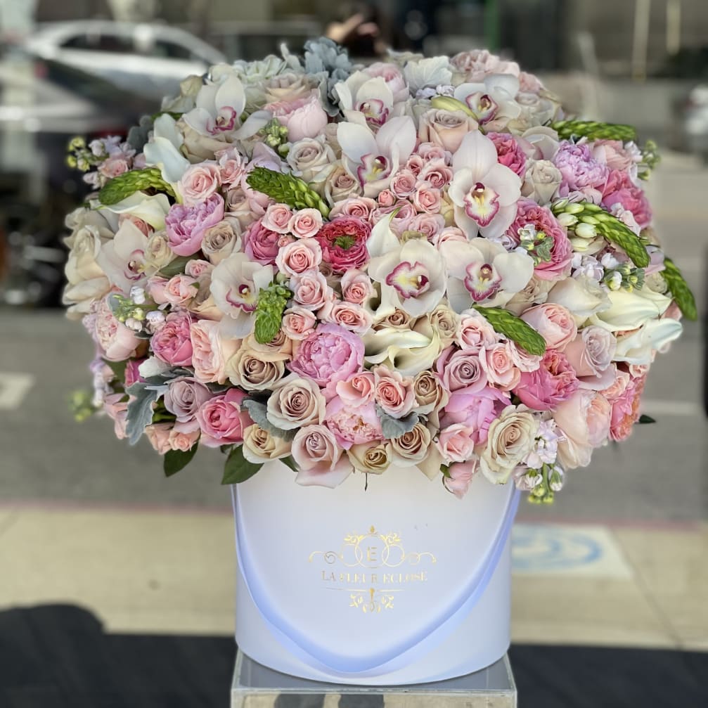 Large pastel bouquet of roses, orchids, and calla lilies in a white hat box