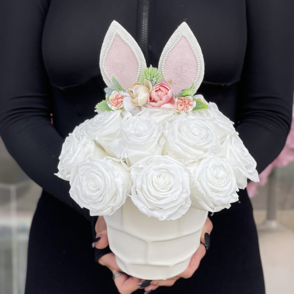 White rose arrangement in a white vase with pink bunny ears