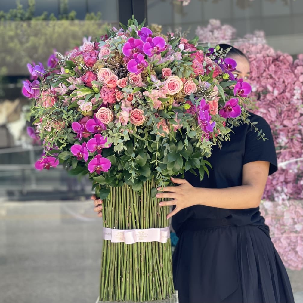 Large bouquet of pink roses and purple orchids held by a person