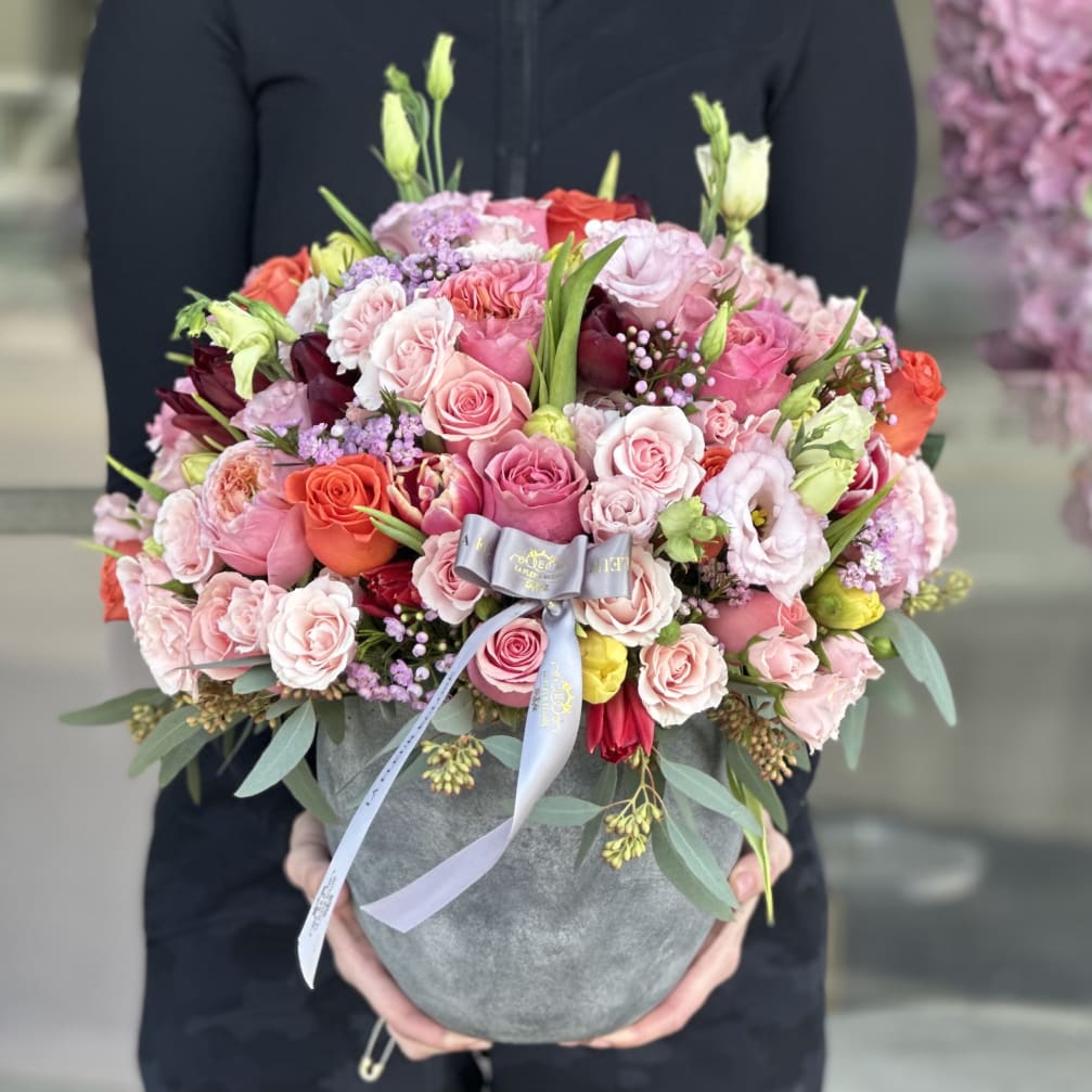 Pink and coral rose bouquet in a gray hatbox with a ribbon