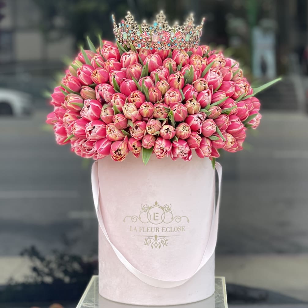 Pink tulip bouquet topped with a jeweled crown in a pale pink hatbox