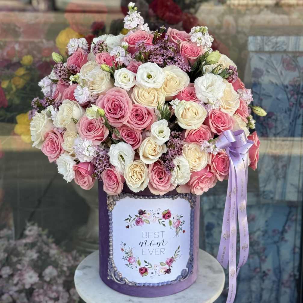 Pink and white rose bouquet in a purple hatbox with a ribbon