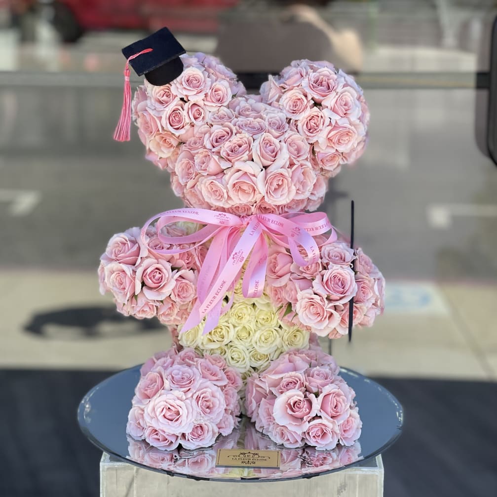 Pink rose teddy bear with a graduation cap and ribbon bow