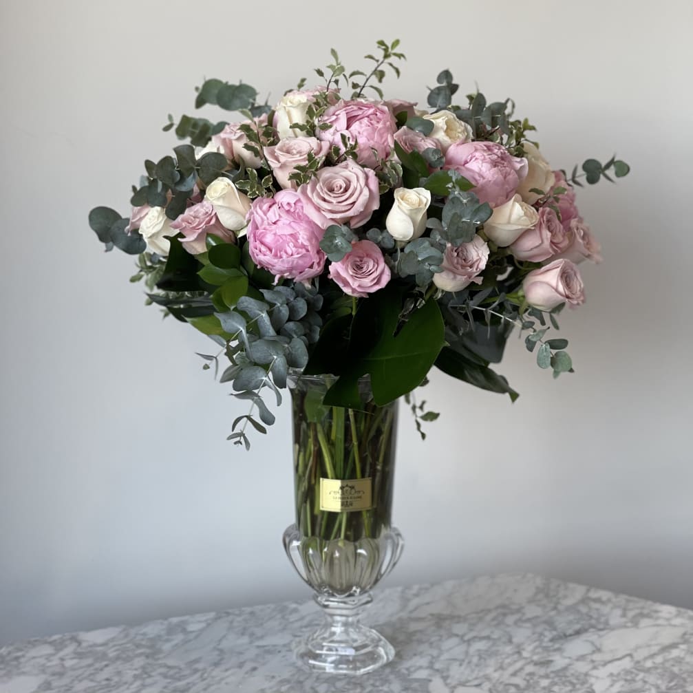 Pink and white roses in a clear glass vase with eucalyptus