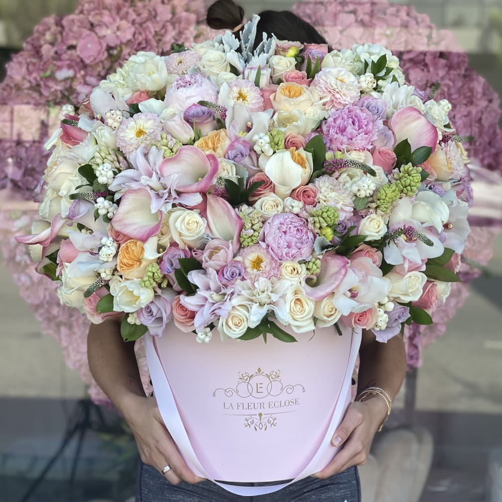 Large pastel bouquet in a pink box held by a person