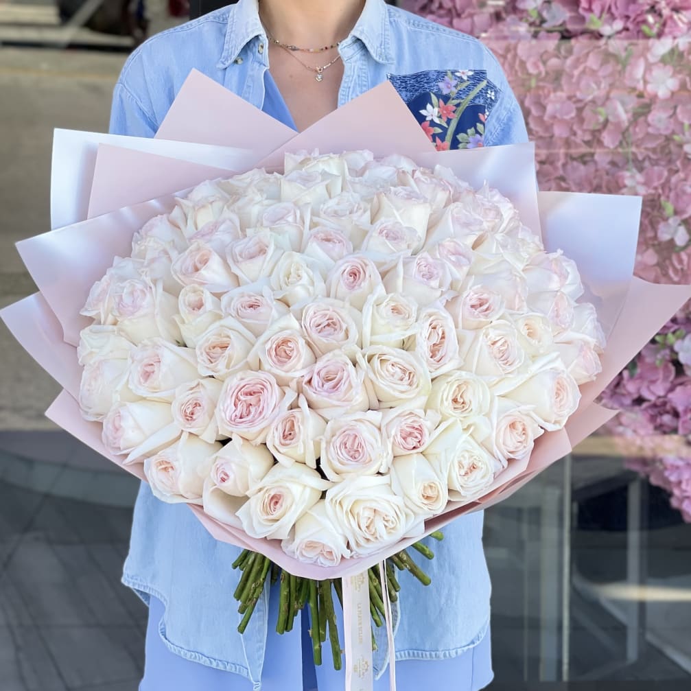 Large bouquet of pale pink and white roses wrapped in pink paper