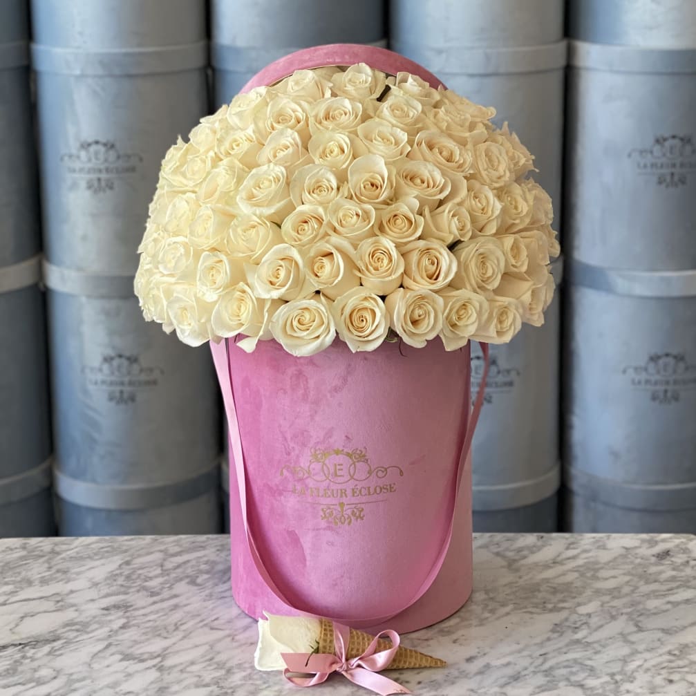Cream rose bouquet in a pink hat box with a small wrapped cone favor in front