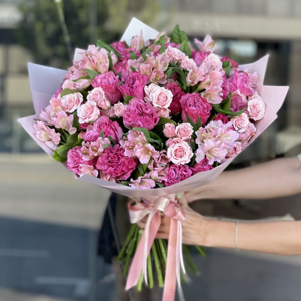 Pink bouquet of roses and alstroemeria wrapped in pale paper