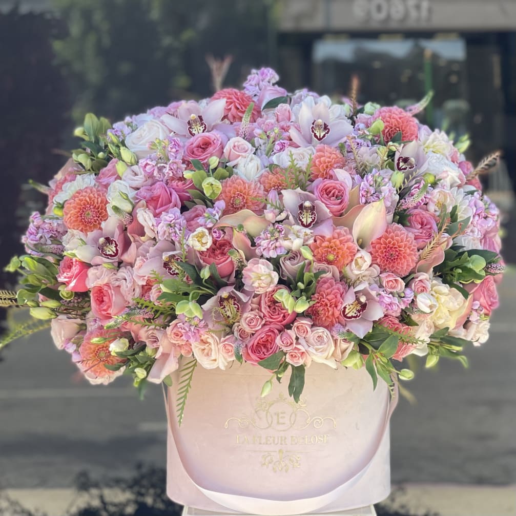 Large pink and white mixed flower arrangement in a round box