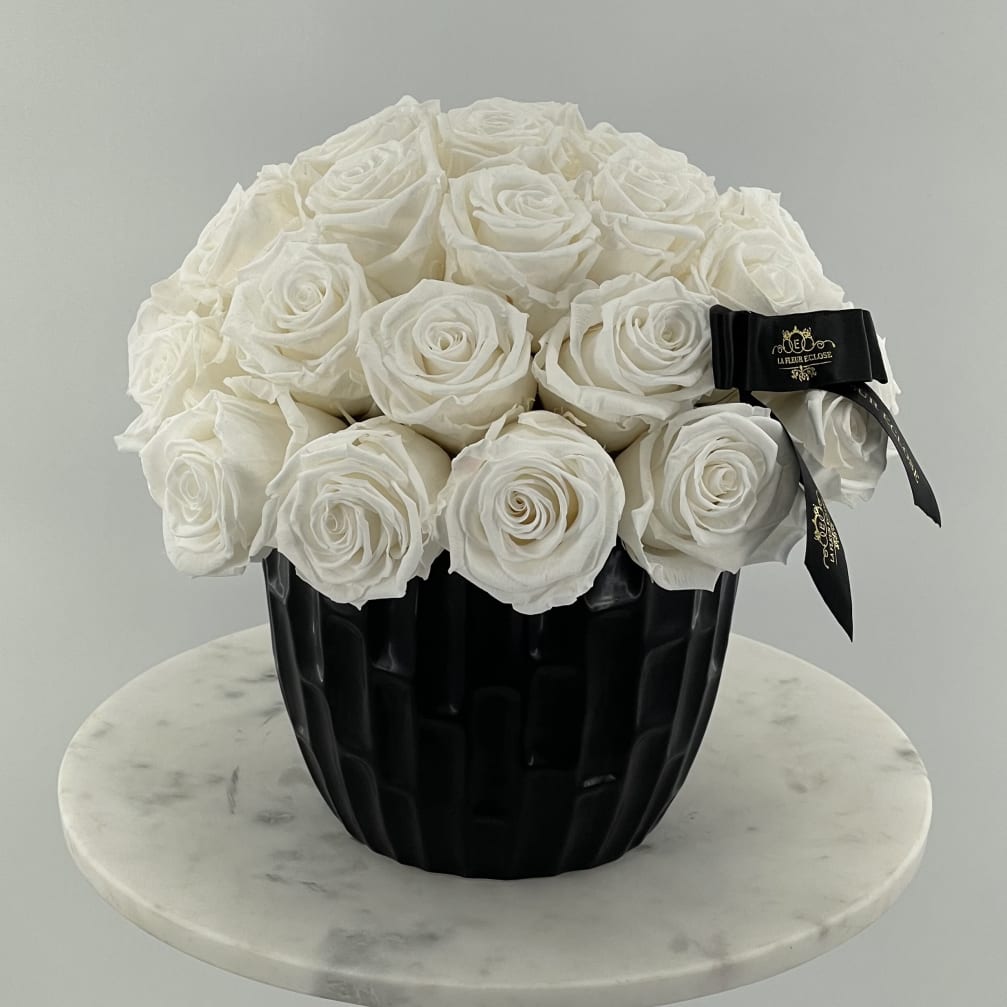 White rose bouquet in a black vase with a ribbon