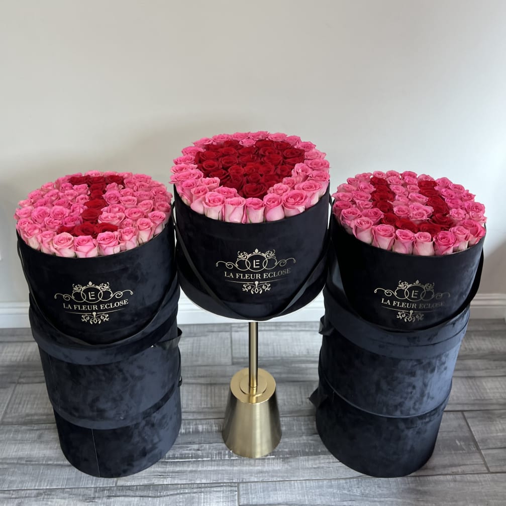 Three round boxes of pink and red roses on stands