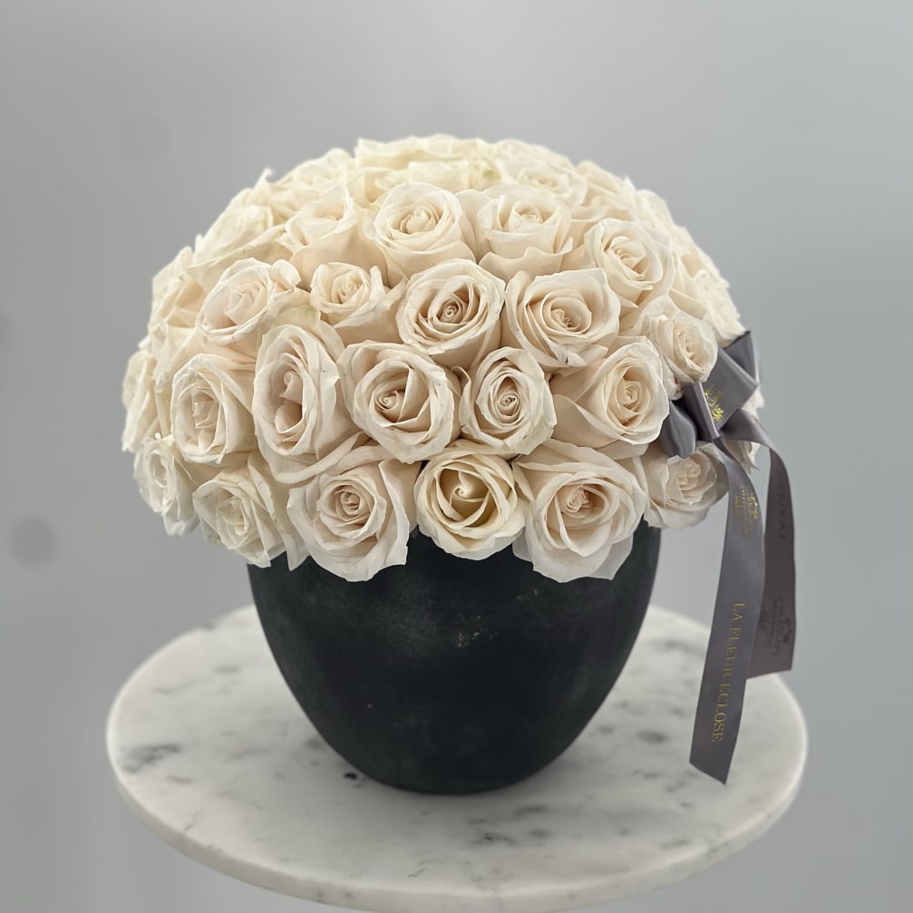 Cream rose bouquet in a black vase with a gray ribbon