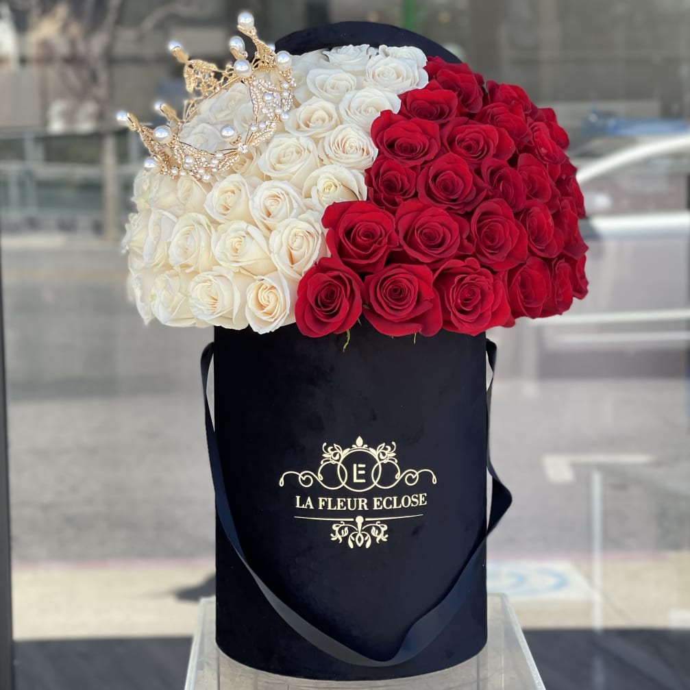 Red and white roses in a black hatbox with jeweled crown accents