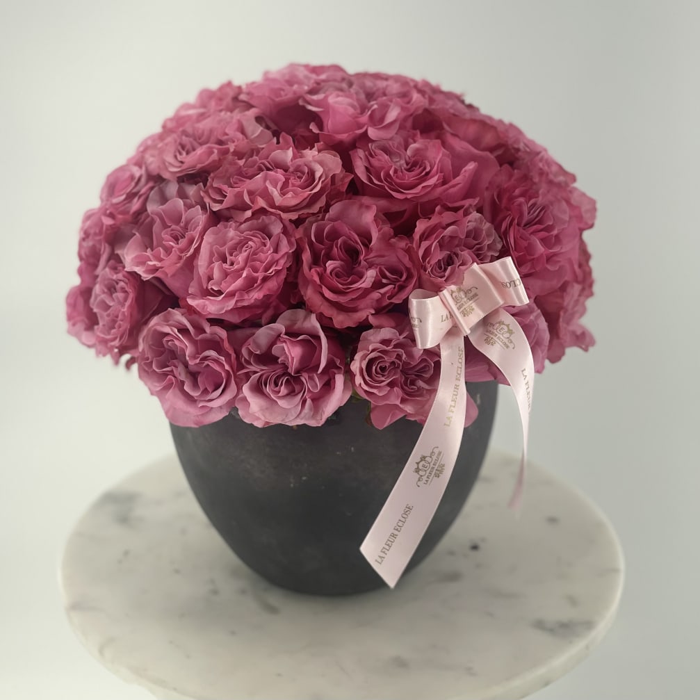 Pink rose bouquet in a black vase with a pale pink ribbon