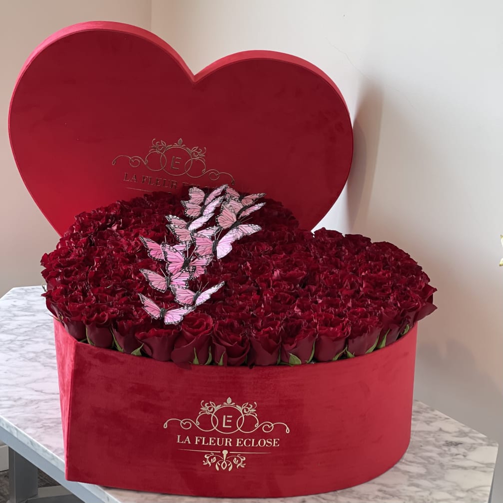 Heart-shaped red box filled with red roses and pink butterfly decorations