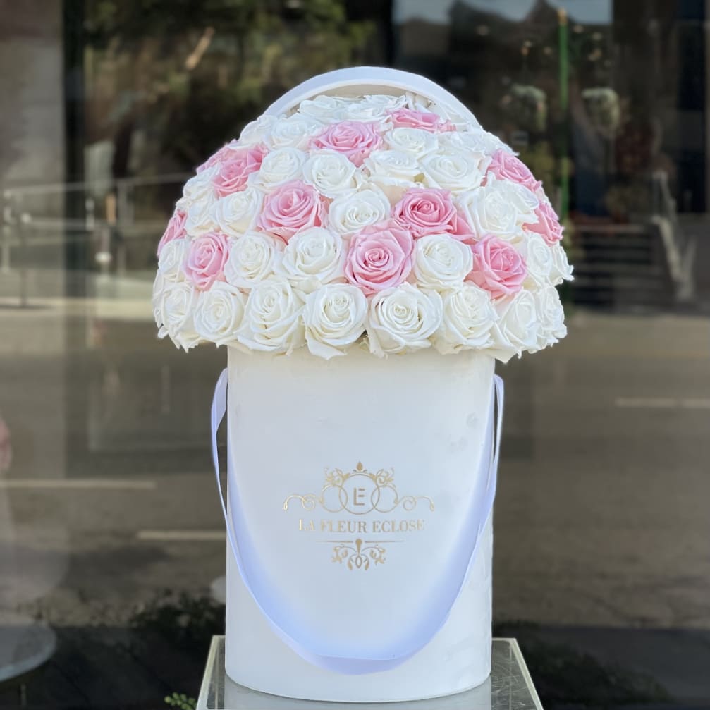 Pink and white roses arranged in a round white hat box