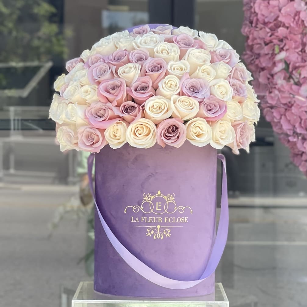 Round bouquet of pink and white roses in a purple hatbox