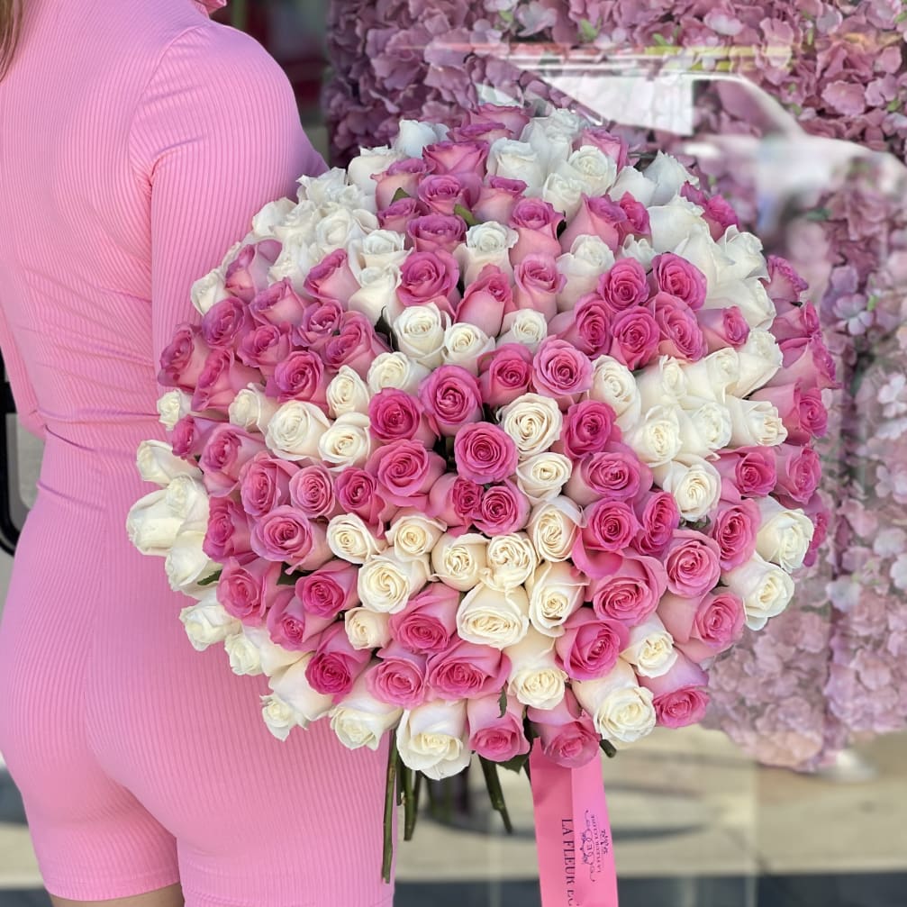 Large bouquet of pink and white roses held by a person in a pink outfit