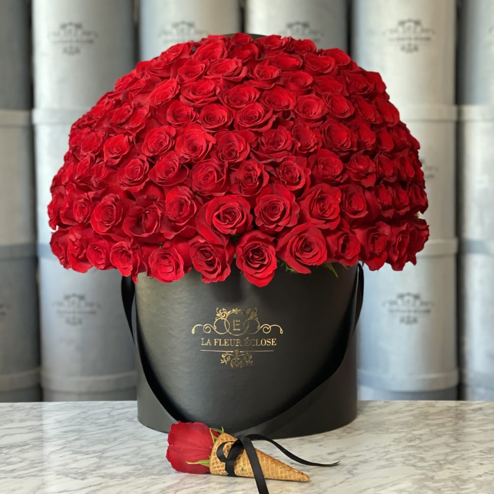 Large dome of red roses in a black hatbox with a single rose at the base