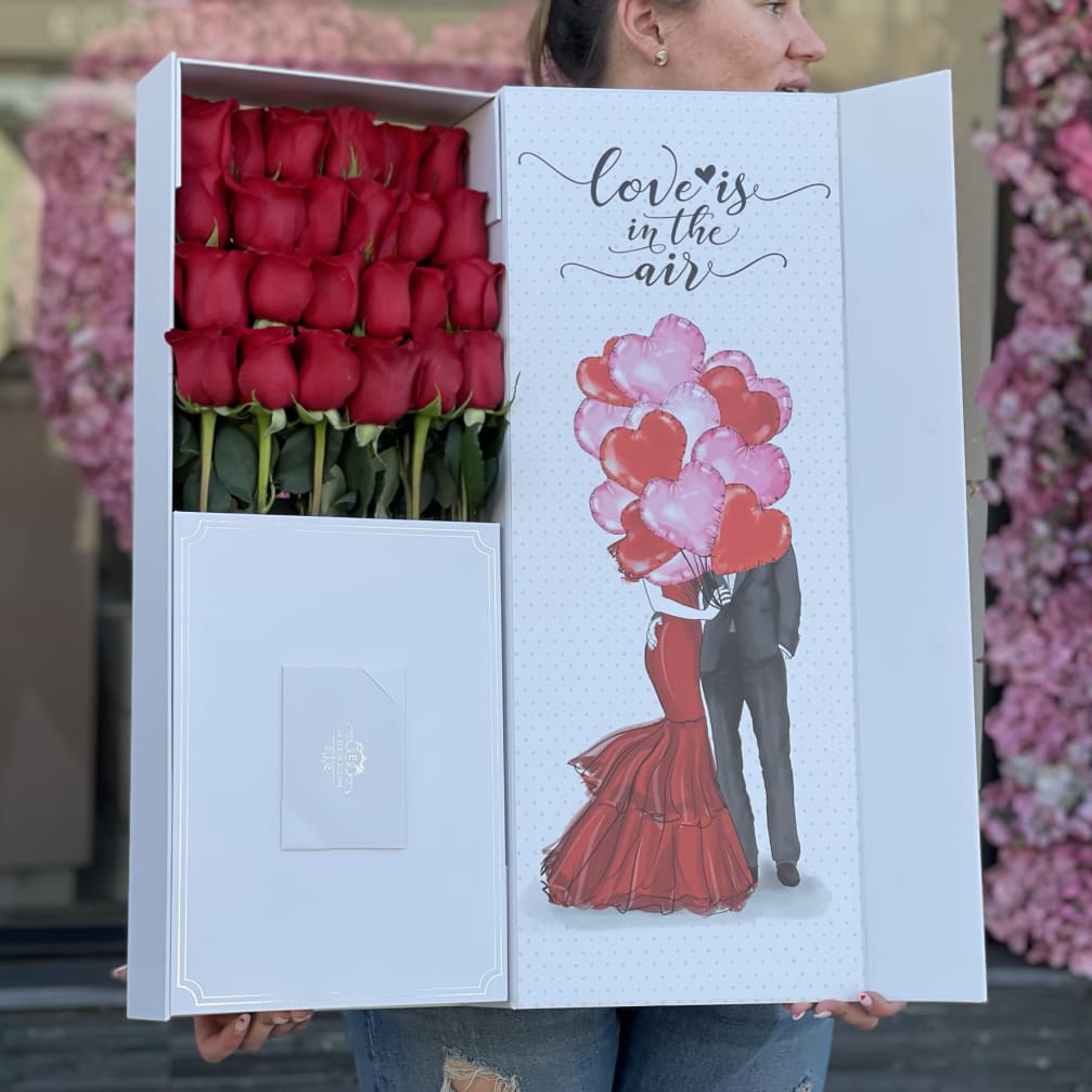 Box of red roses with a love-themed card and envelope