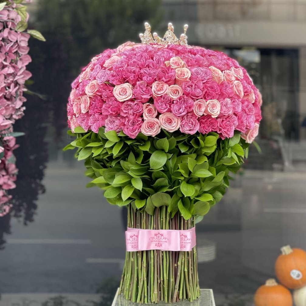 Pink rose bouquet shaped like a crown-topped dome with green leaves at the base