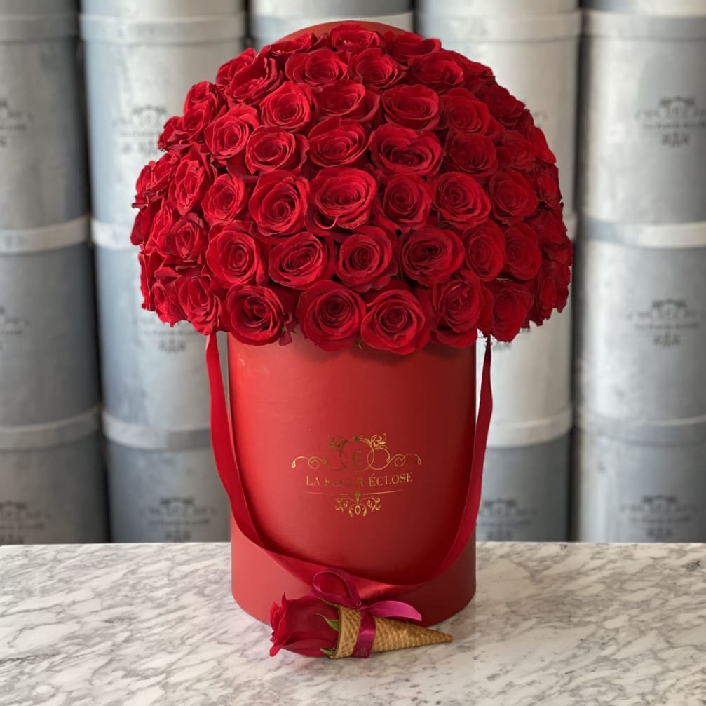 Red rose arrangement in a red hat box with a small rose corsage