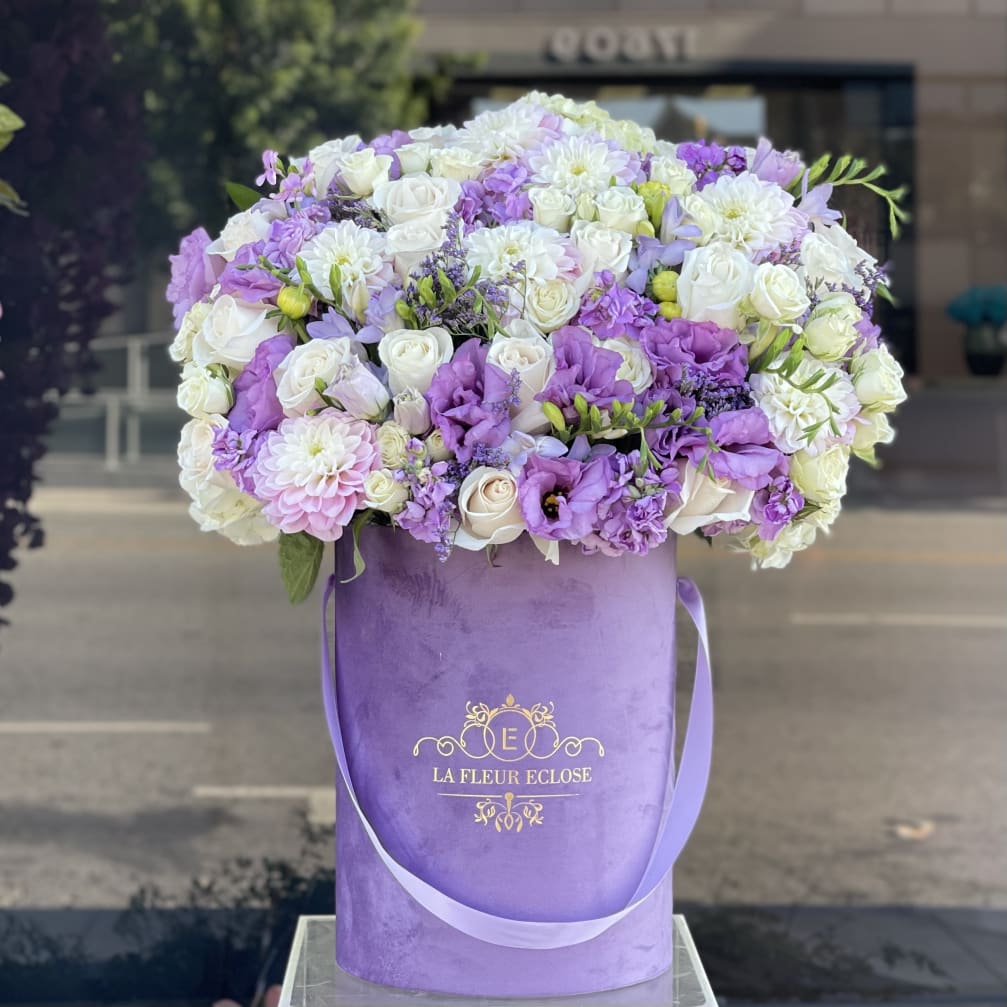 Lavender and white flower arrangement in a purple hatbox