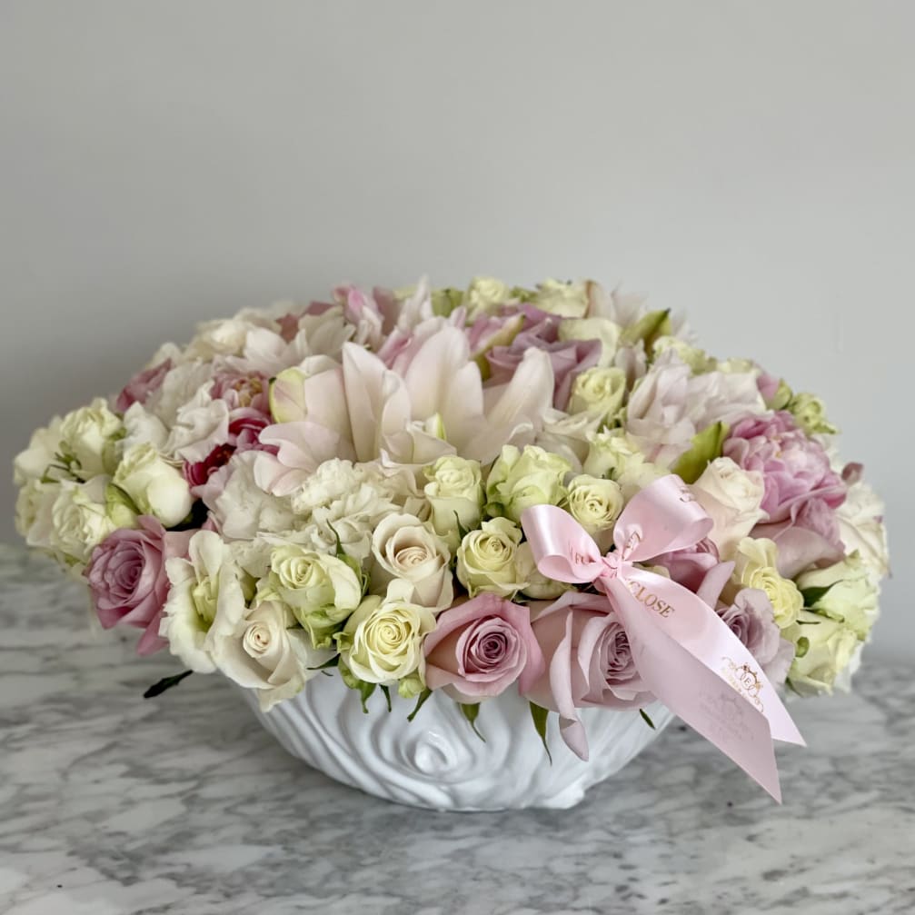 Low floral arrangement of pink and white roses in a white bowl vase