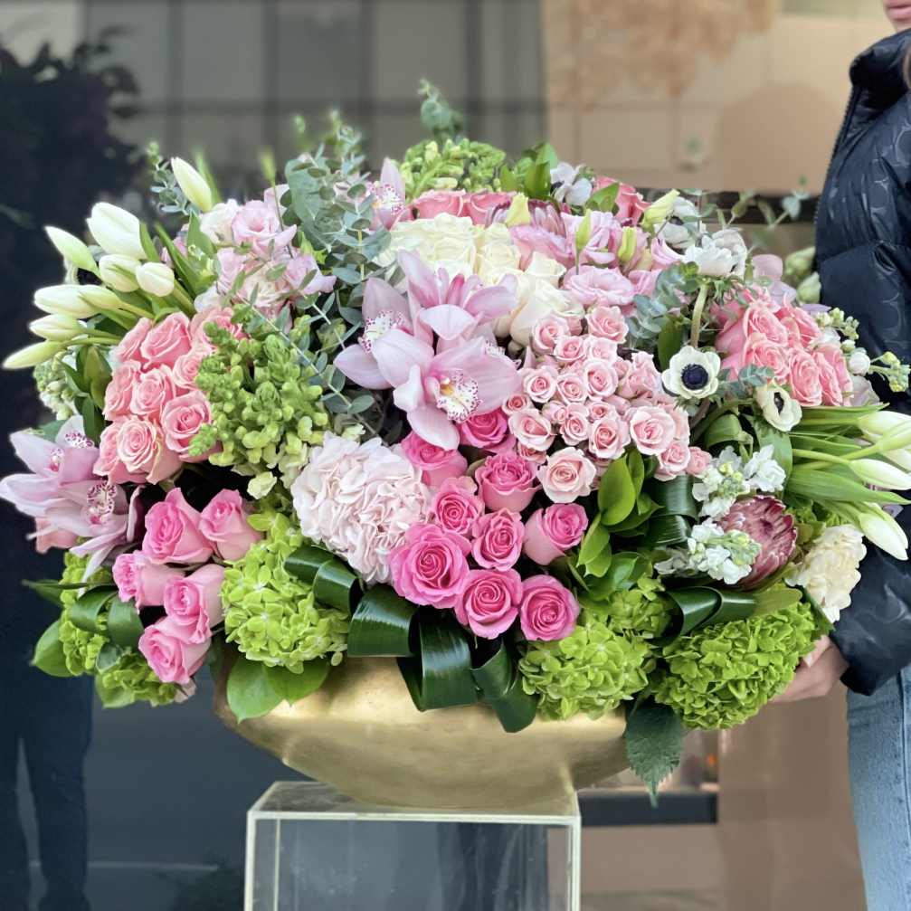 Large pink and white floral arrangement in a gold vase