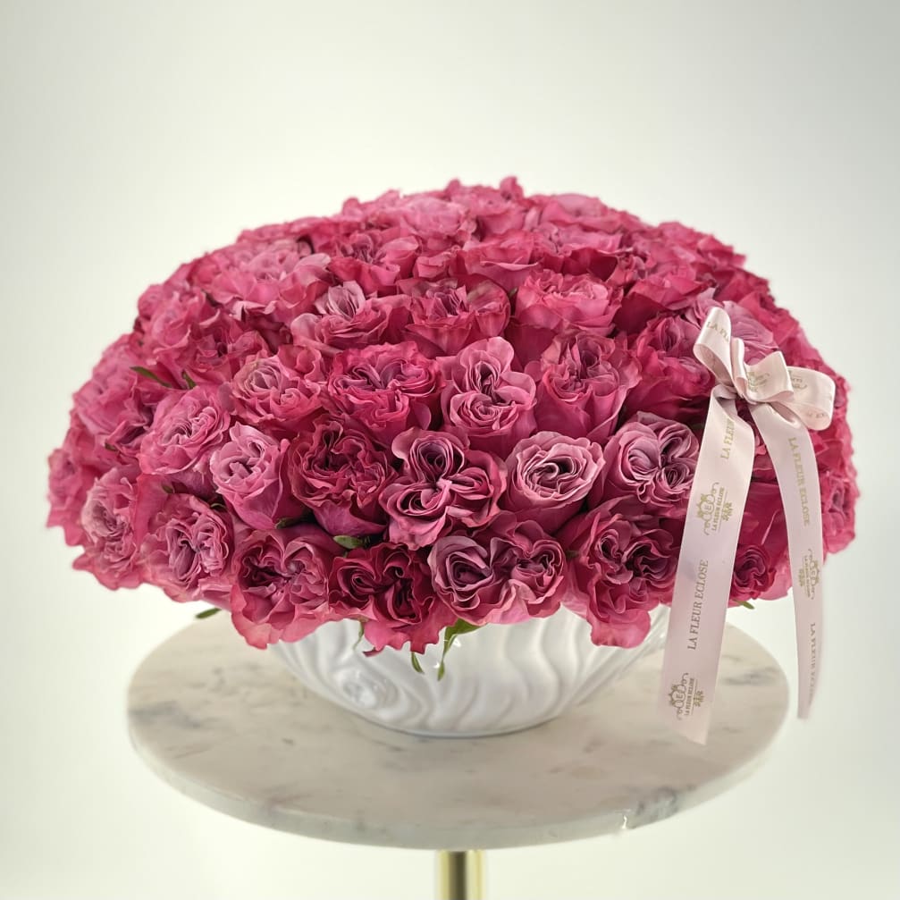 Large dome of pink roses in a white vase with a ribbon bow