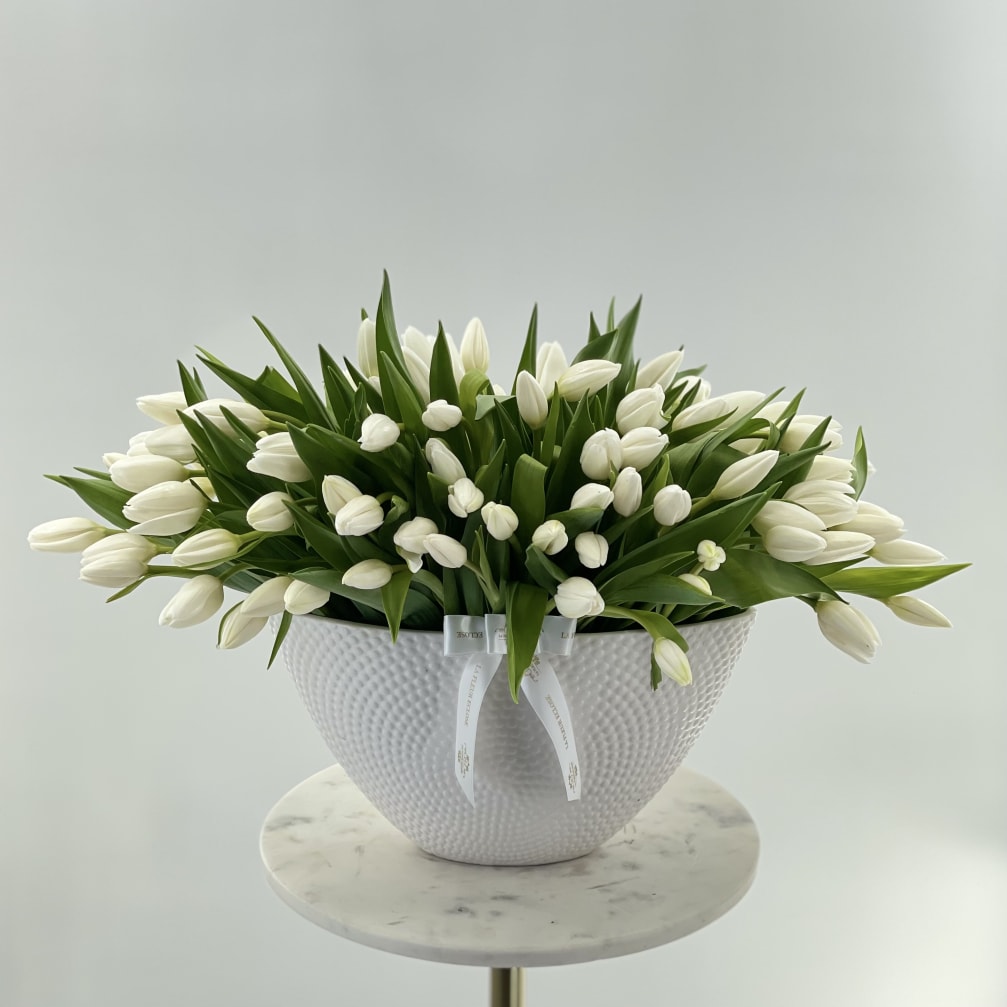 White tulips arranged in a textured white bowl vase
