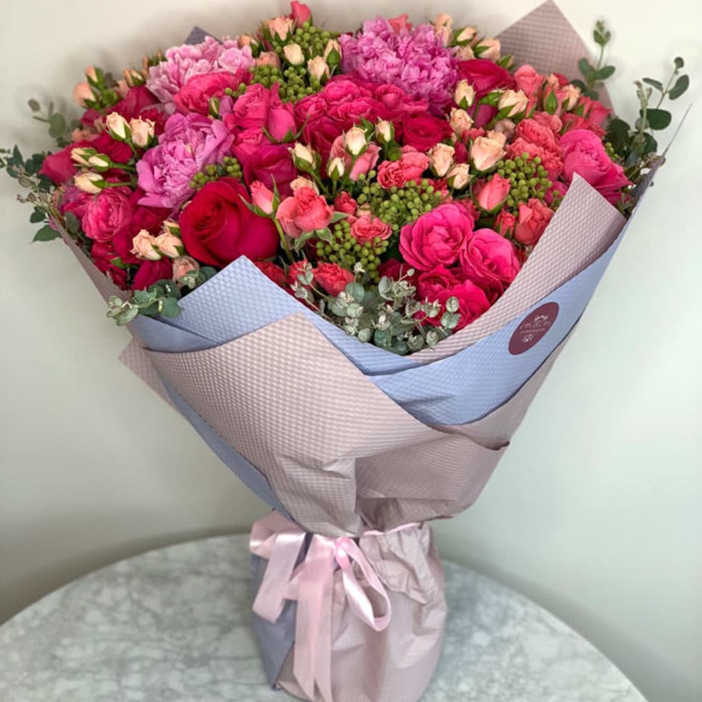Large bouquet of pink and red roses wrapped in pastel paper
