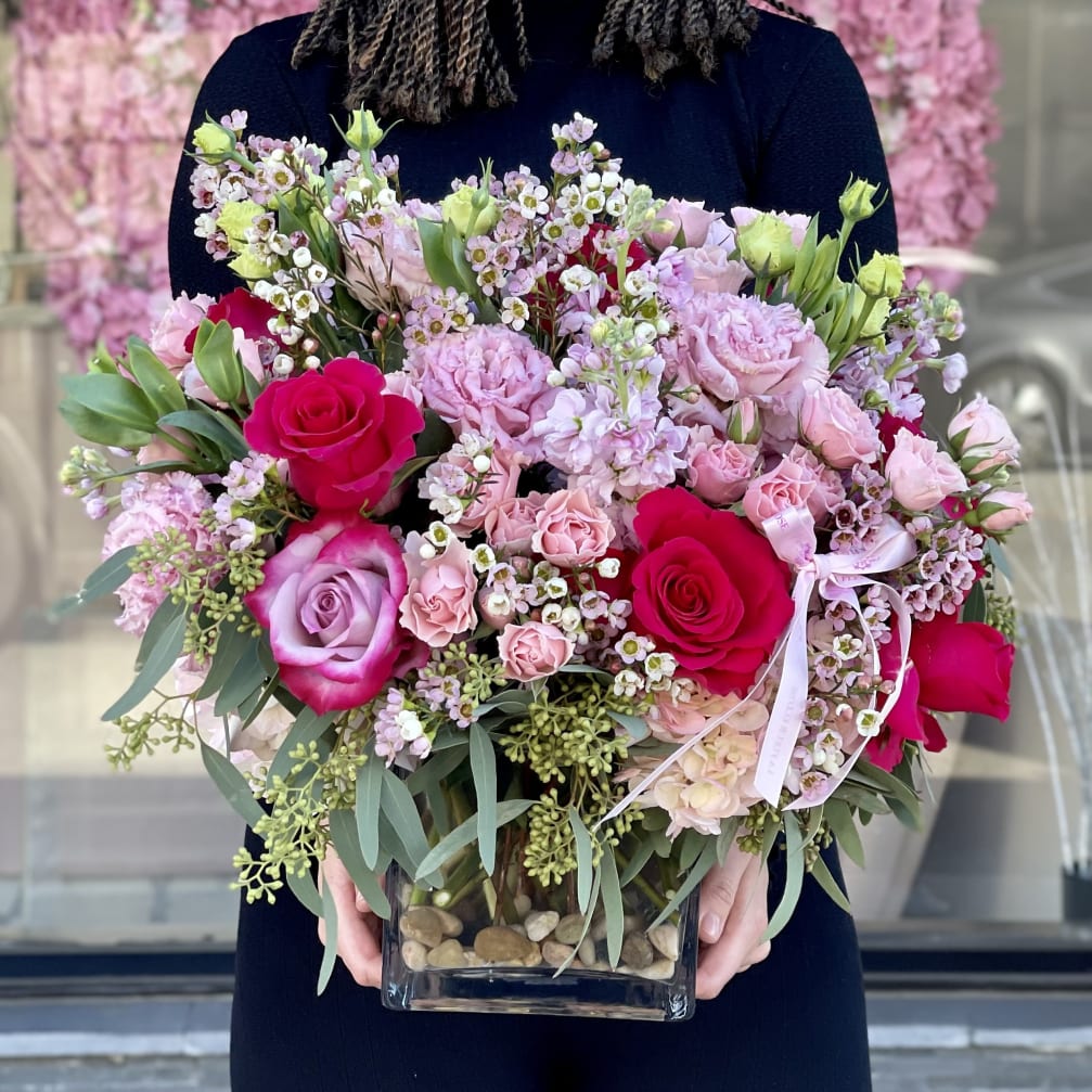 Pink and red rose bouquet in a glass vase with small white blossoms