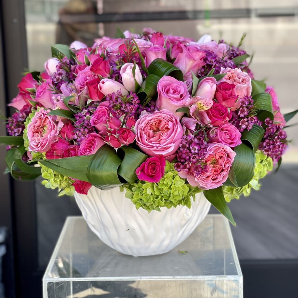 Pink rose arrangement in a white vase with green leaves