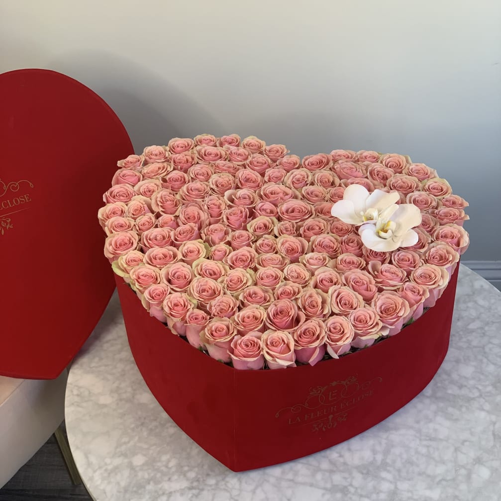 Heart-shaped box filled with pink roses and white orchids