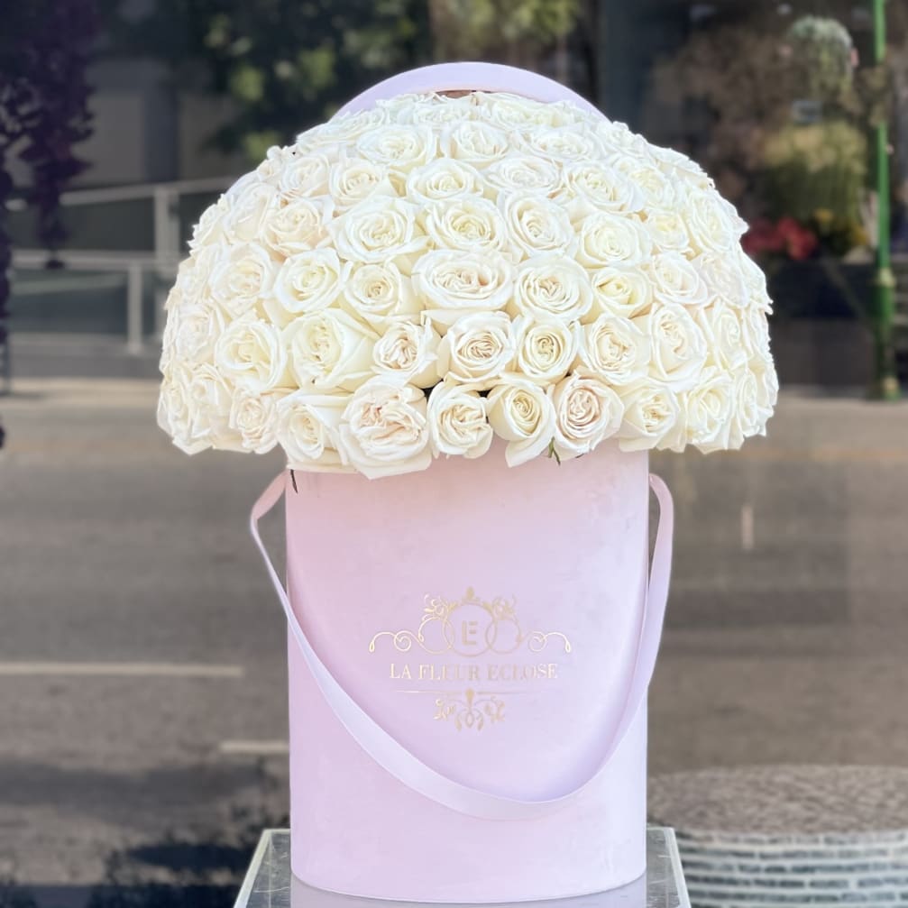 White rose bouquet in a pink hat box with ribbon handles