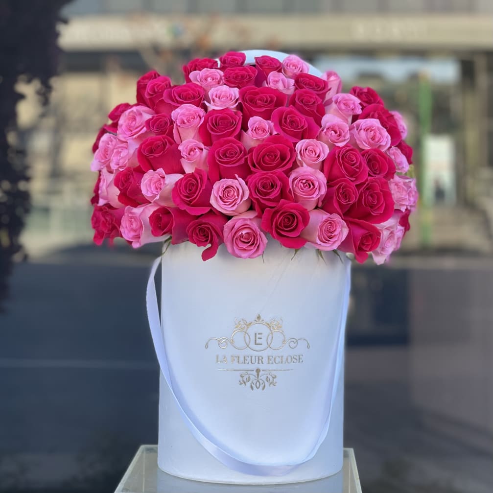 Pink and hot pink roses arranged in a white hat box