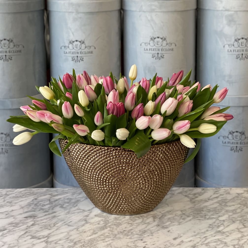 Pink and white tulips arranged in a gold textured vase