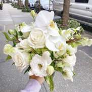 White rose and orchid bouquet held outdoors