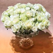 White rose bouquet in a clear glass pedestal vase