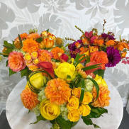 Three colorful floral arrangements with roses and dahlias on a round table