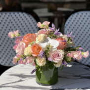 Pink and peach roses with white orchids in a glass vase