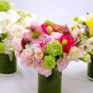 Three colorful floral arrangements in green glass vases