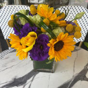 Bouquet of yellow and purple flowers in a clear glass vase