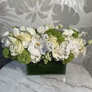 White roses, orchids, and calla lilies in a green rectangular vase