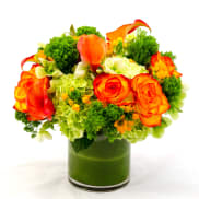 Orange roses and calla lilies in a green glass vase